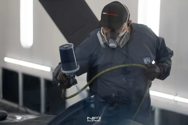 An NFI Empire painter laying down the Roadster's finish in the paint booth